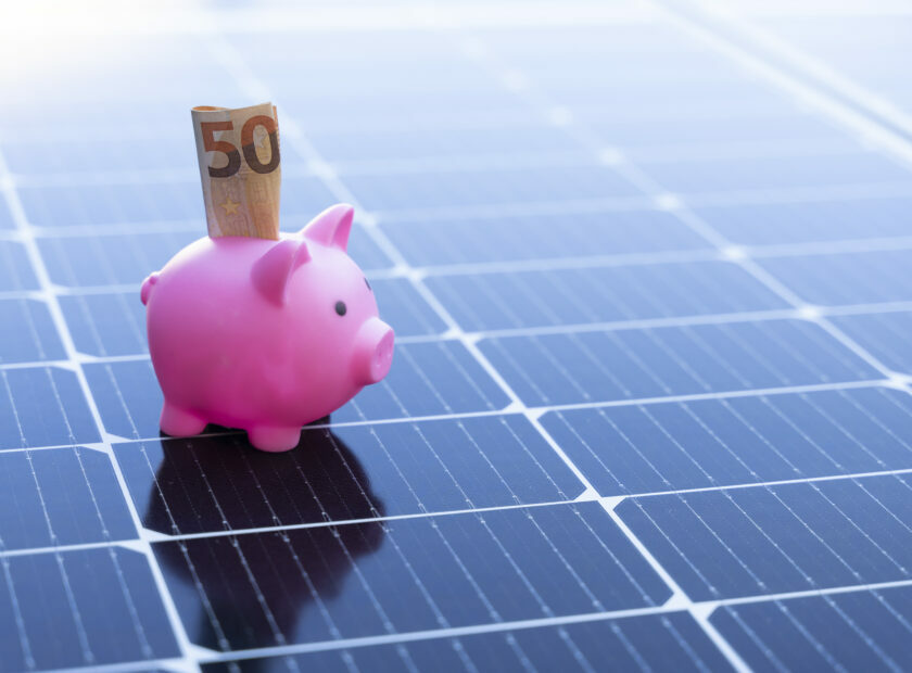 Energy saving concept with solar panels and a piggy bank with fifty euro