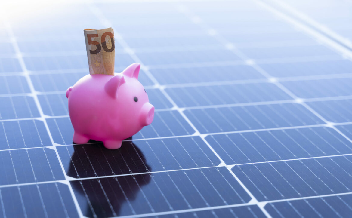 Energy saving concept with solar panels and a piggy bank with fifty euro